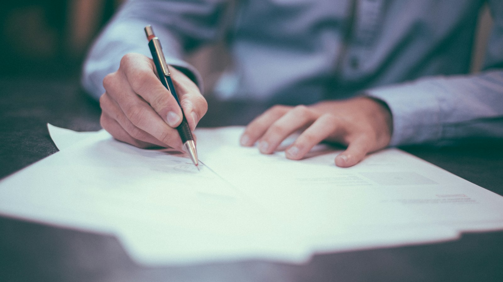 A home buyer reviewing a signed contract of purchase and sale at a kitchen table in Vernon