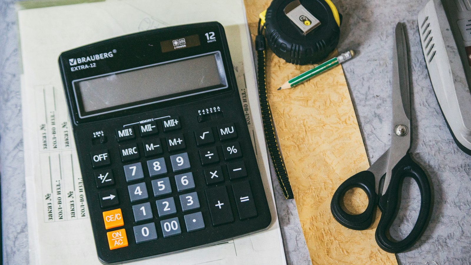 House keys and a calculator on a kitchen table, representing the tax side of selling a home in BC