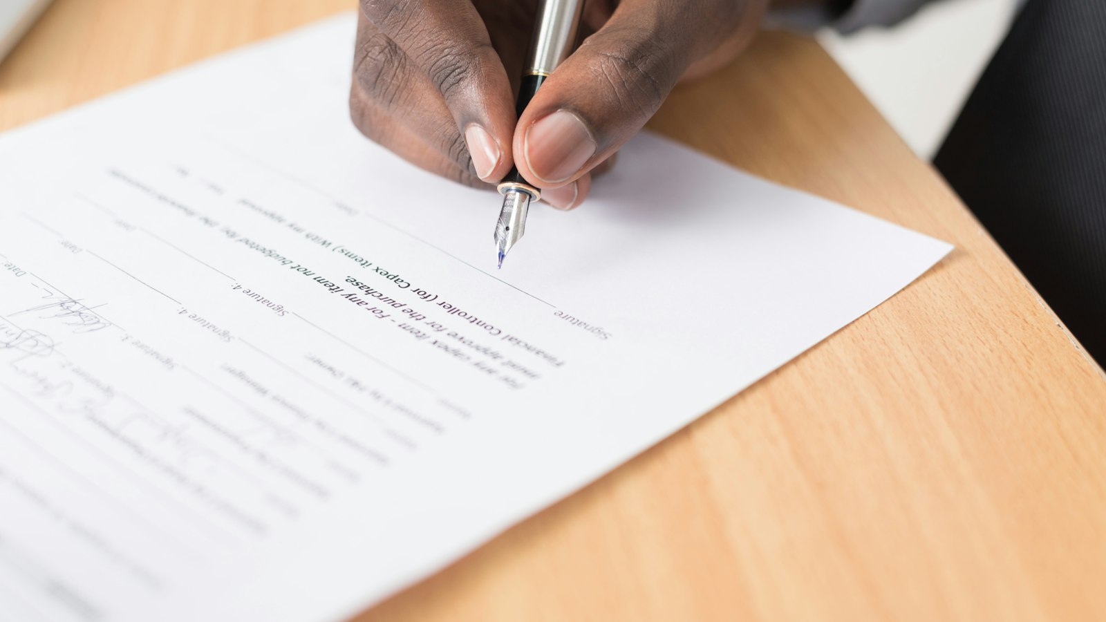 A person reviewing a contract with a pen in hand before signing a real estate agreement in Vernon
